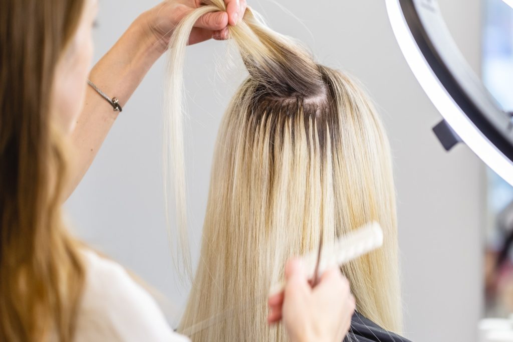 Blonde hair extensions procedure in beauty salon