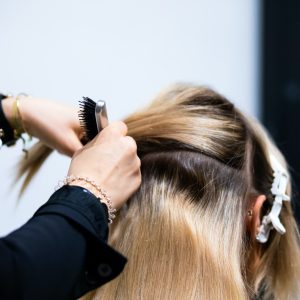 Professional hairdresser making hair extensions for blonde girl in a beauty salon